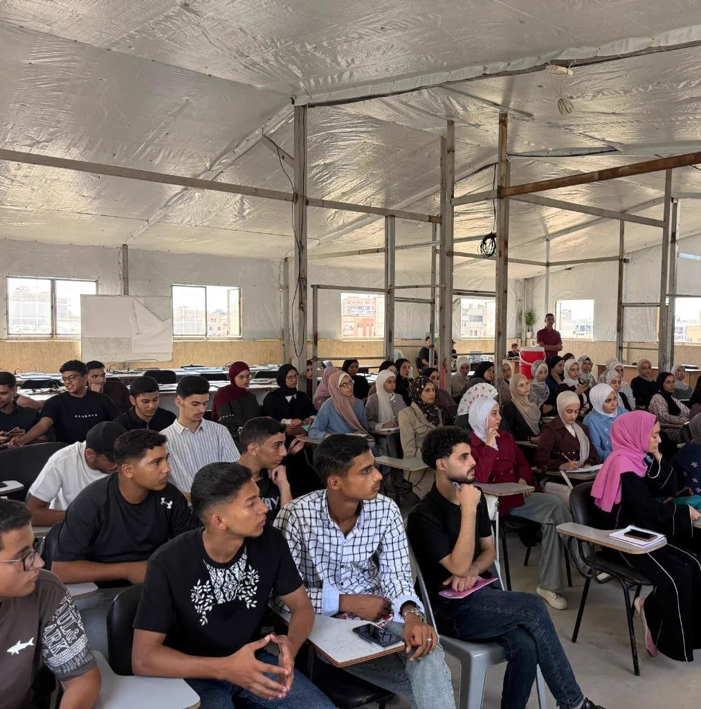 A full hall of students, men and women, listening during a Misbar course