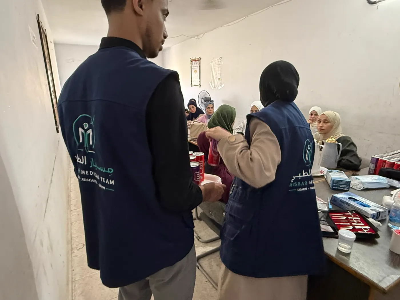 Two Misbar volunteers in team vests inside a training room
